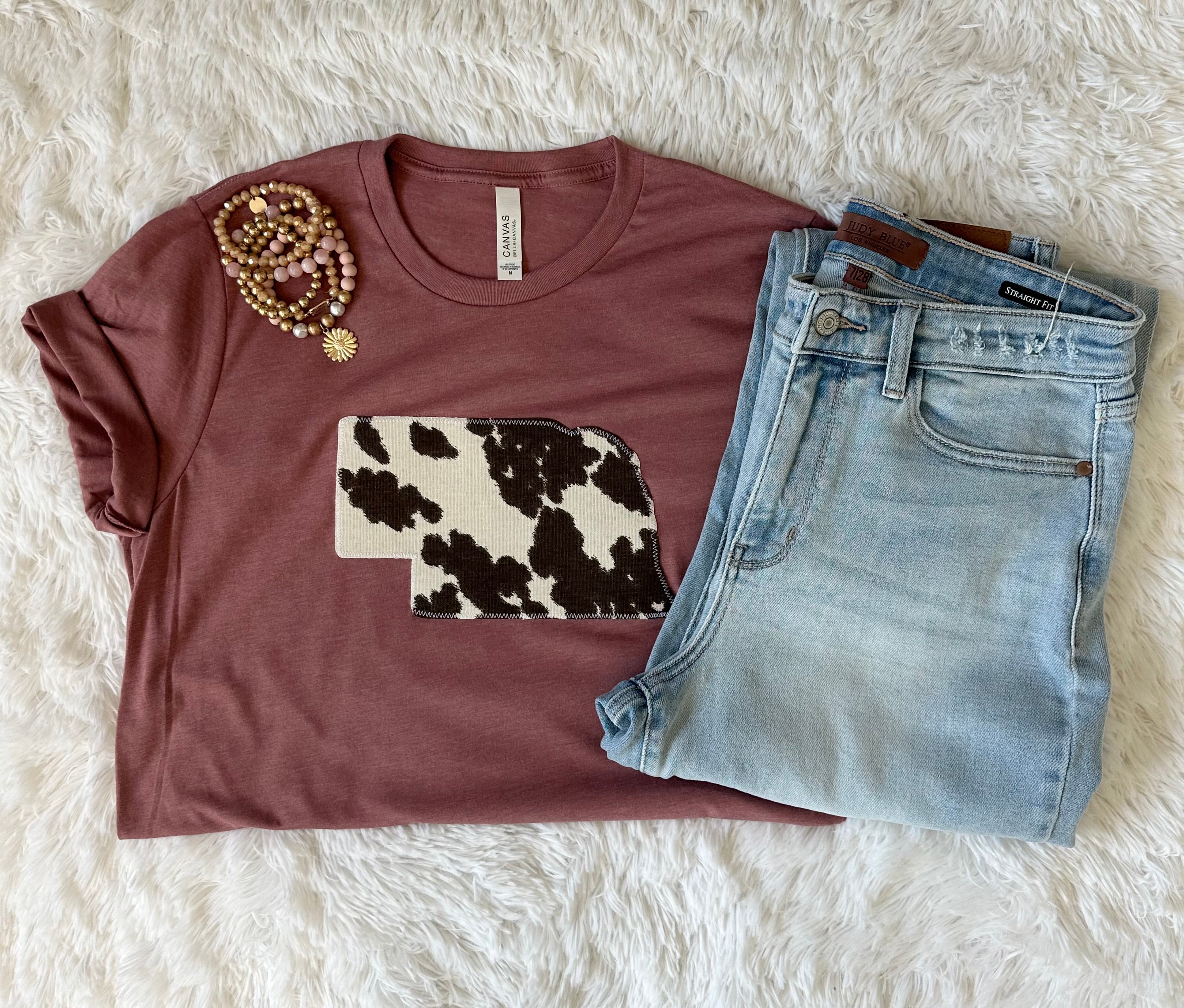 Mauve Cow Print State Tee on a Bella + Canvas shirt, featuring a unique hand-sewn state fabric design.