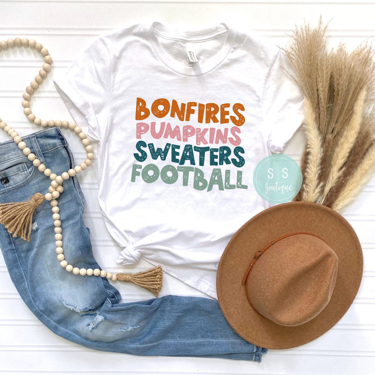 Fall Tee with bonfires, pumpkins, sweaters, and football design, printed on Bella + Canvas fabric.