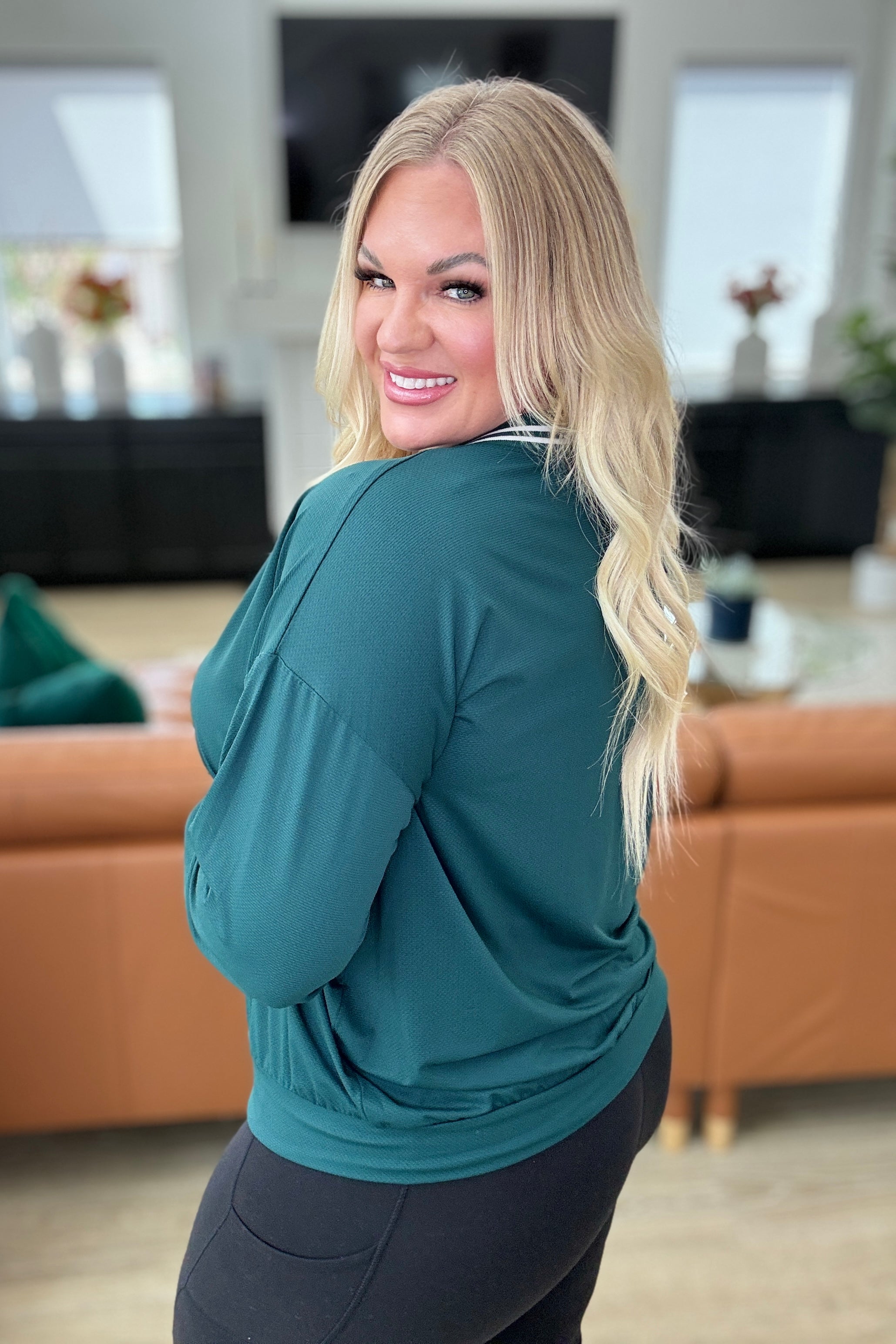 slight side view of All Out Comfort V-Neck Pullover in Midnight Green featuring a contrast V-neckline, drop shoulders, banded cuffs and hem. High-stretch, breathable nylon fabric.