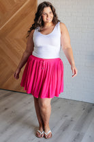 plus side model wearing Bet Your Bottom Dollar Skirt in Hot Pink, pleated Bulgari fabric with elastic waistband, drawstring, and attached shorts.