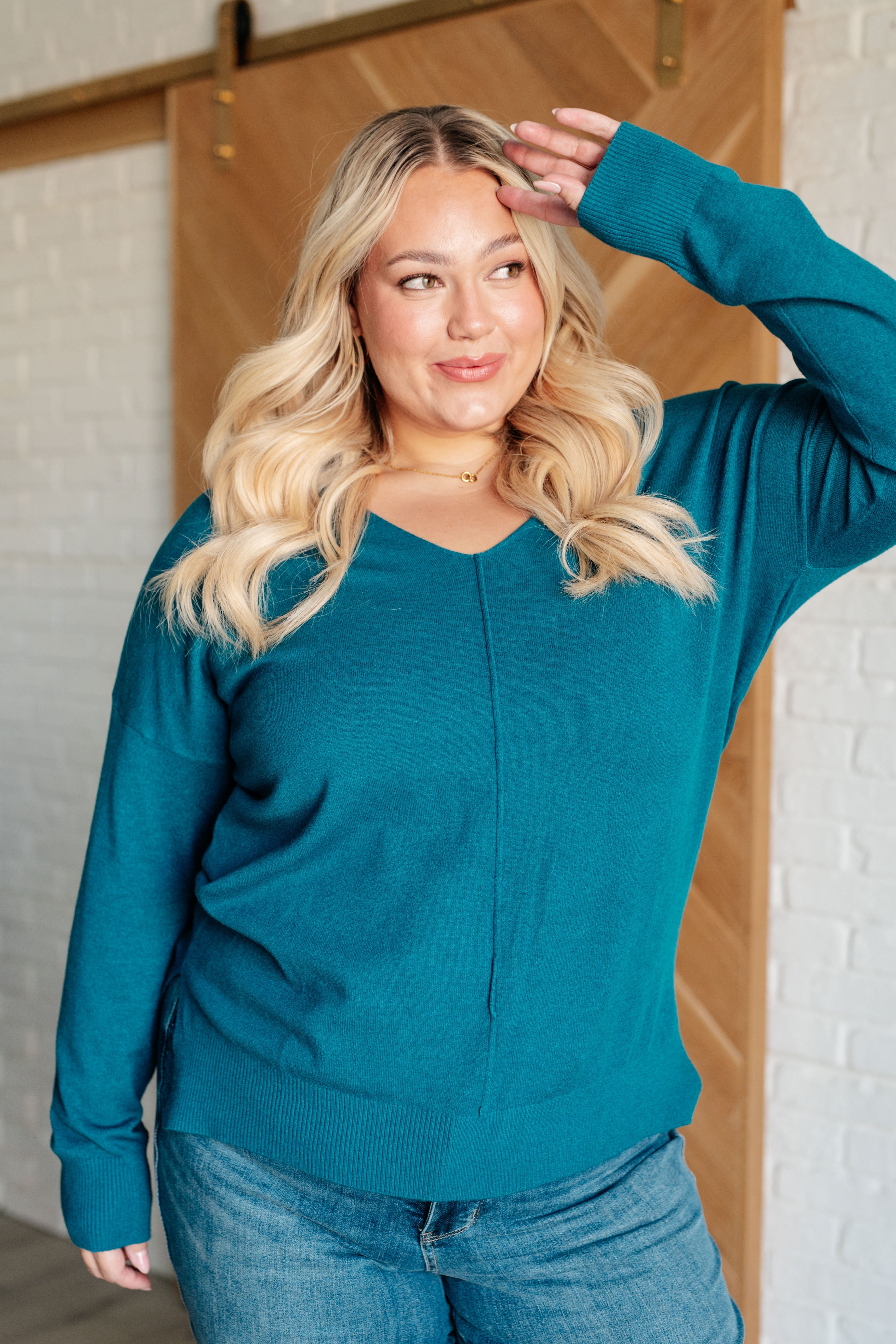 close up view of larger size model wearing Heather Ocean Teal Center Seam Sweater with V-neckline, front seam detail, dropped shoulders, ribbed cuffs, hemline, and side slits for a relaxed and cozy look.